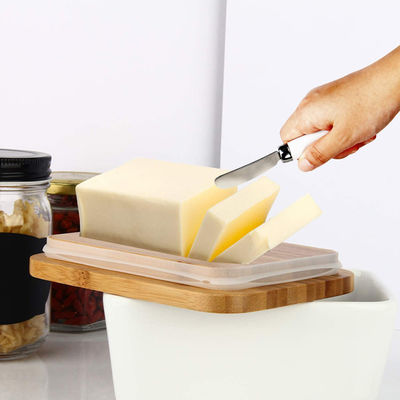 キッチン カウンターのためのふたそしてナイフが付いている白い陶磁器のバター皿