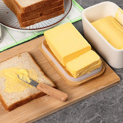 キッチン カウンターのためのふたそしてナイフが付いている白い陶磁器のバター皿